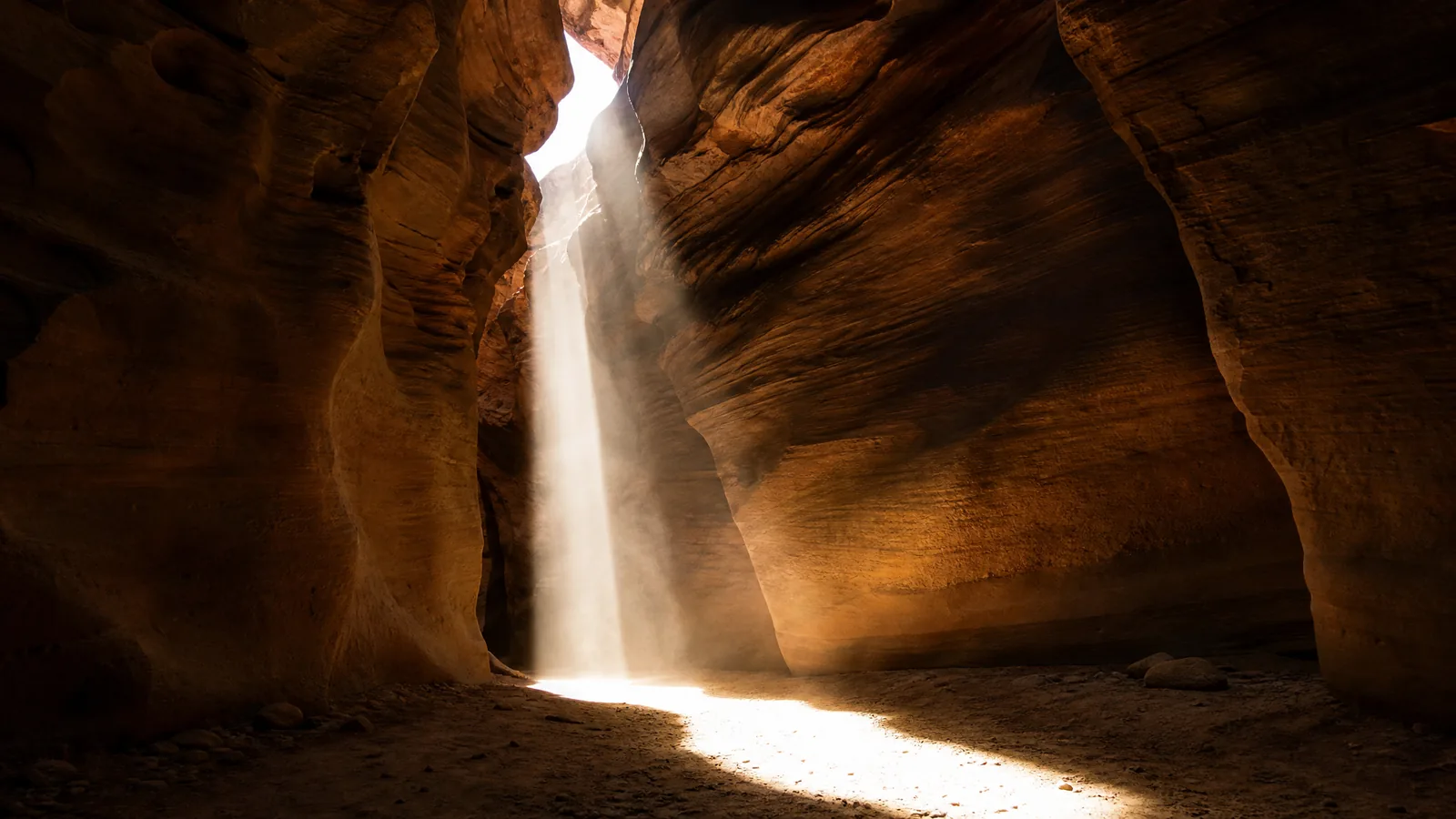 A narrow slot canyon with one hard shaft of noon sun on the floor