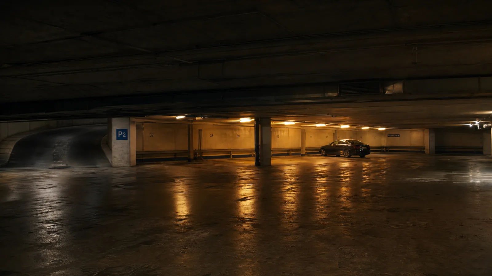 An underground parking level, sodium pools on damp concrete